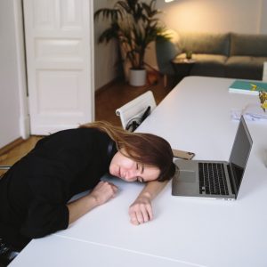 a woman is sleeping on her desk in front of a laptop