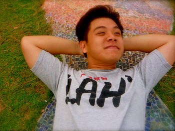 A young person lying on the grass with hands behind his head