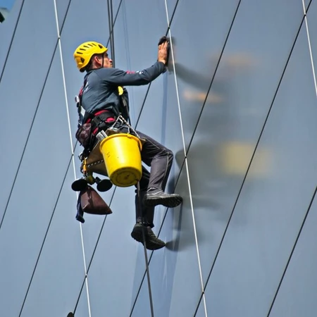 A man held in the air by safety harness cleaning windows of a high-rise building