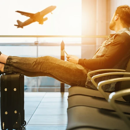 A man waiting for his flight, feet resting on the bag