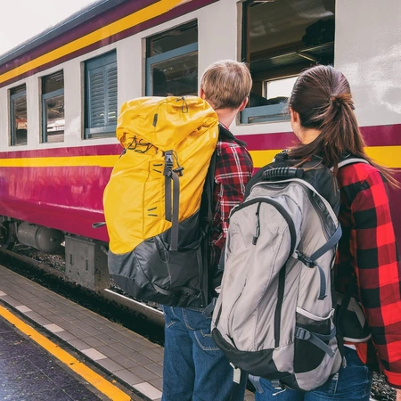 Two backpackers at a train platform waiting to board the train car